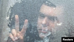 A Belarusian opposition supporter flashes a victory sign from a police bus near a detention center in Minsk.