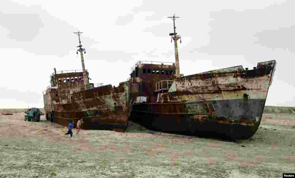 Children run past rusting ships abandoned in sand that once formed the bed of the Aral Sea near the village of Zhalanash, in Kazakhstan.