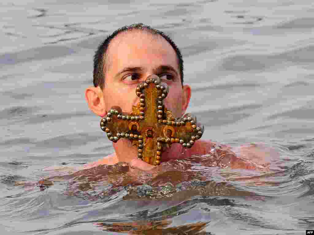 A believer in Turkey kisses a wooden cross thrown into the water by Orthodox Patriarch Bartholomew. - Some Orthodox Christians in Turkey took part in Epiphany Day celebrations on January 6 by jumping into the Bosphorus to retrieve a cross cast into the water by a priest.