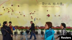 Visitors walk past a wall with a map showing the species of peony in Belt and Road Initiative countries at a horticultural exhibition at the Beijing Expo 2019 in Beijing.