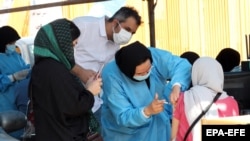 People receive a COVID-19 vaccine at a drive-in vaccination station at the Azadi sport complex in Tehran on September 16.