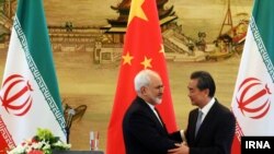 Iranian Foreign Minister Mohammad Javad Zarif (left) shakes hands with his Chinese counterpart, Wang Yi, at a bilateral meeting in Beijing. Iran has in recent months increasingly reached out to China in the face of growing U.S. pressure to isolate Tehran. (file photo)