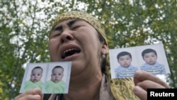 An ethnic Uzbek refugee shows photos of her missing grandsons as she stands on the Kyrgyz-Uzbek border, near the village of Yorkishlak, on June 15.