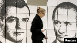 A woman walks by a panel made of cardboard boxes, displaying President Dmitry Medvedev (left) and Prime Minister Vladimir Putin in Rostov na Donu, 21Oct2010