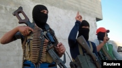 Masked Sunni gunmen pose with their weapons during a patrol outside the city of Fallujah, which remains largely in rebel hands.