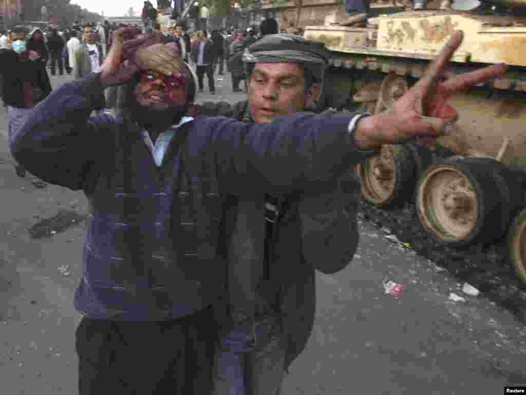 An injured antigovernment protester is helped during clashes on Tahrir Square.