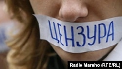 A woman attends a protest in Russia against Internet censorship, with a sign over her mouth reading "censorship."