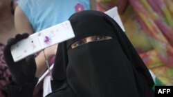 A veiled woman holds up her mobile phone. In Pakistan's conservative former tribal areas and beyond, women have become easy targets of schemes to illegally clone mobile SIM cards. (file photo)