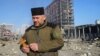 Chaplain Mykola Medinsky holds a cross and a rosary at the site of a military strike on a shopping center in Kyiv on March 21, 2022.