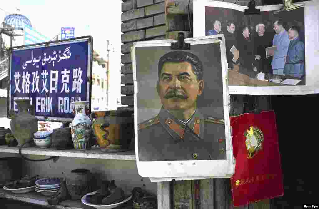 A picture of Soviet dictator Josef Stalin hangs beside one of Chairman Mao in a small street market. - Dominated by a gigantic statue of Mao, old Kashgar has seen many changes in recent decades, including the construction of a main street running through the old town center.