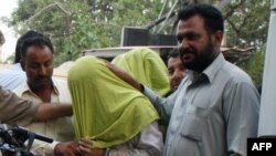 Pakistani policemen escort suspected Taliban militants to a press conference in Karachi in May.