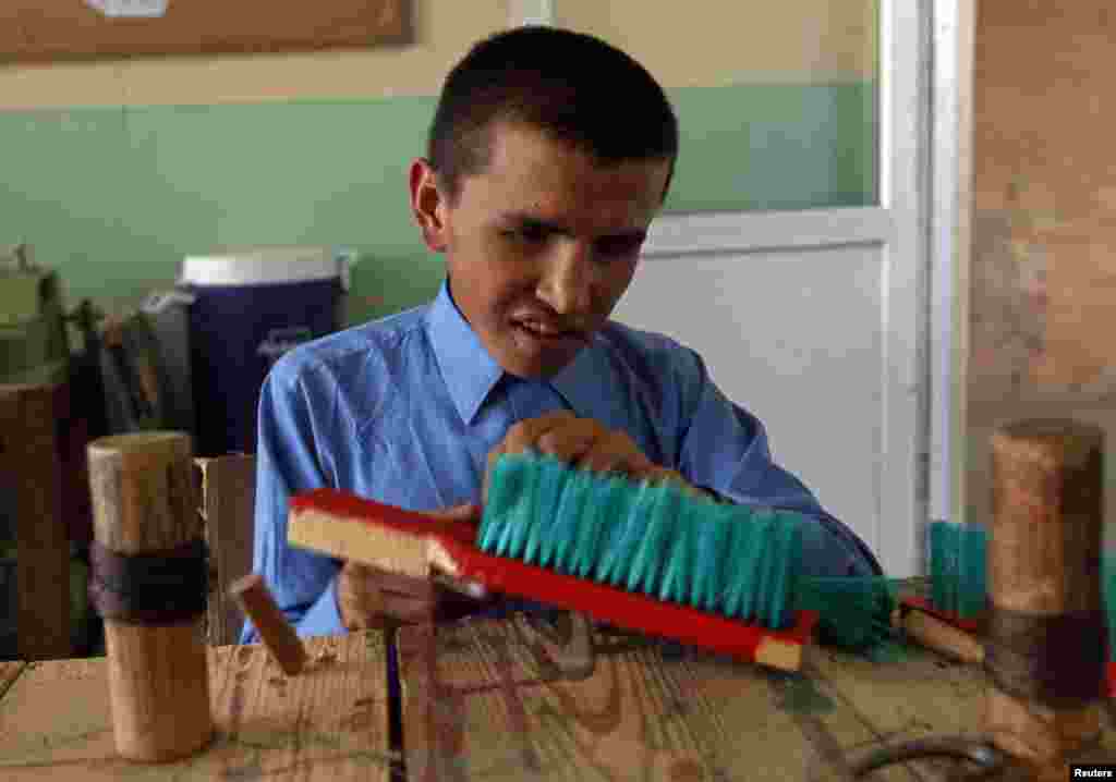 A blind student weaves a cleaning brush at the Kabul Blind School.