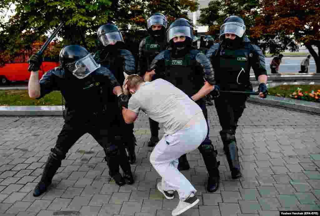 A demonstrator is grabbed by riot policemen in Minsk.