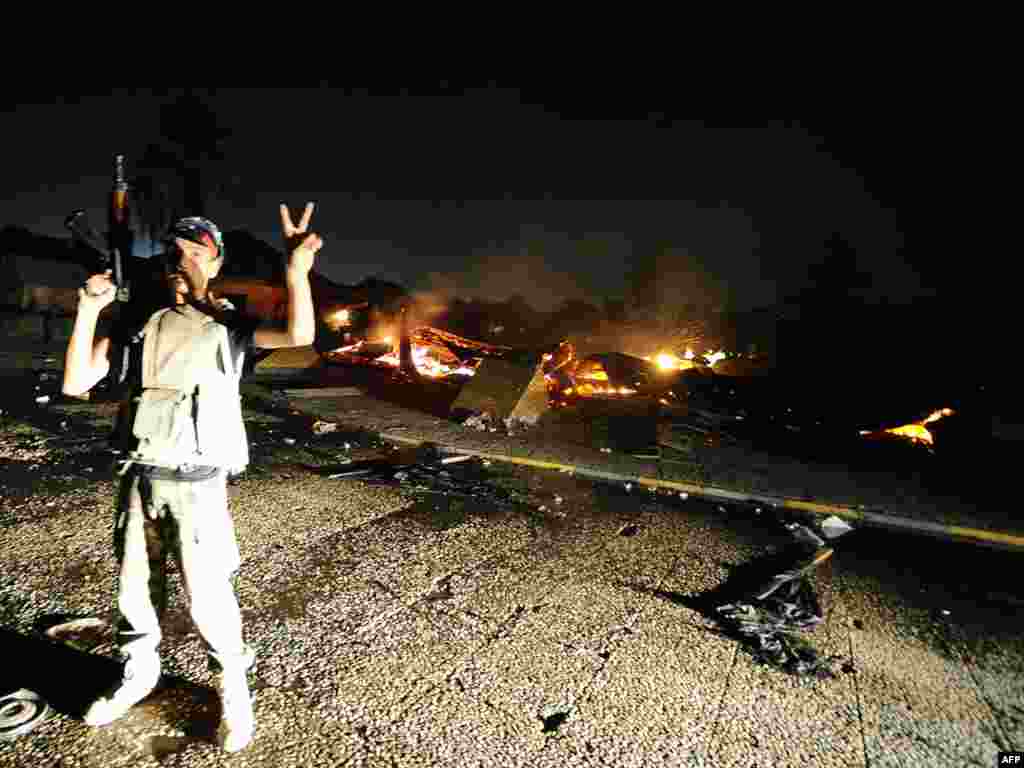 A Libyan rebel flashes the victory sign after overrunning Muammar Qaddafi&#39;s fortified Bab al-Aziziya headquarters. 