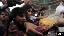 Pakistani children displaced by floods receive food aid at a camp set up by volunteers. But aid has not reached all the areas affected by the floods.