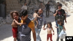 Syrian men carry injured children amid the rubble of destroyed buildings following reported air strikes on the rebel-held neighborhood of Al-Mashhad in the northern city of Aleppo on July 25.