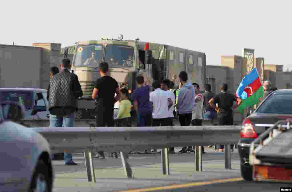 People line up along a roadside to greet Azerbaijani service members in the capital, Baku.