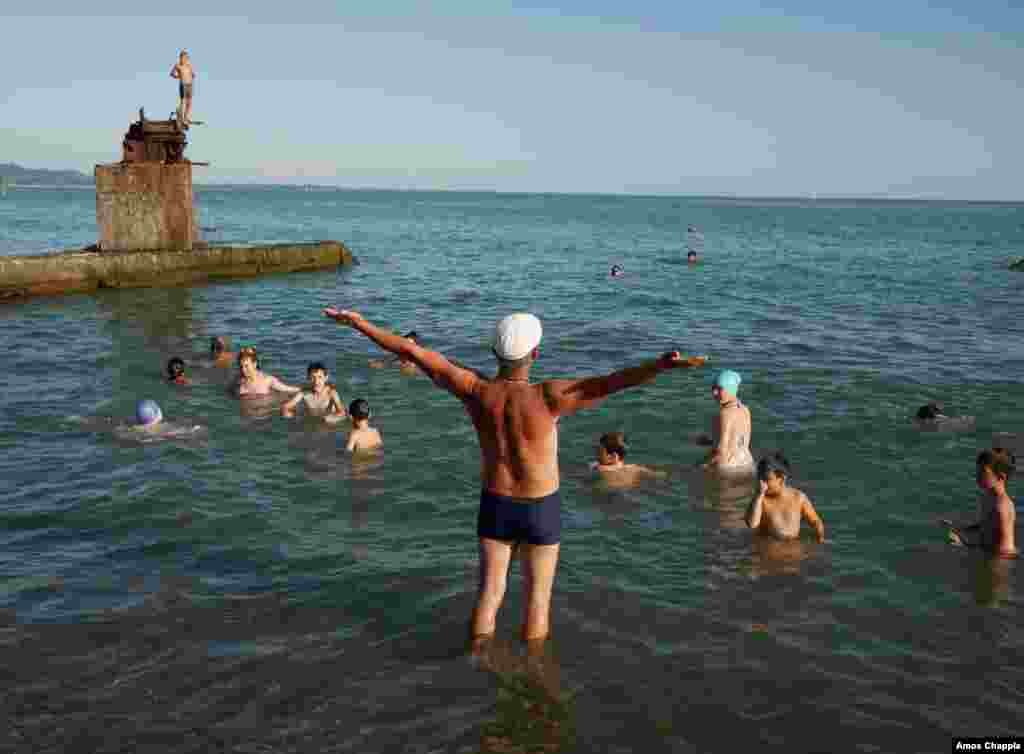 Swimming instructor Victor Zadarozhny demonstrates the backstroke to his young students on the beach in Sukhumi. In the Soviet days, he taught in a nearby swimming pool, but the war and subsequent economic collapse ruined the facility.