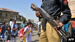 A Pakistani policeman stands guard as students leave school in Karachi