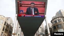 A giant outdoor screen shows Chinese President Xi Jinping attending the closing session of the National People's Congress in Beijing on March 11.