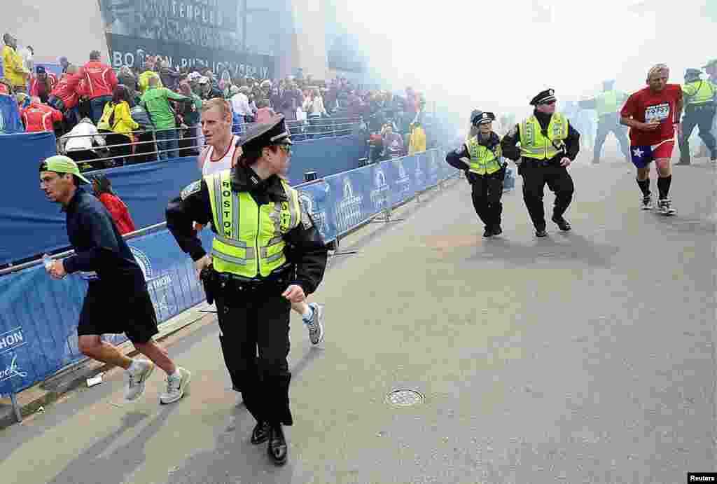 Police and runners react after two explosions at the Boston Marathon.