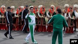 Turkmen President Gurbanguly Berdymukhamedov (center) waves to the media during the starting ceremony in May 2016 for a 500-day nationwide horse race, which was organized as part of Ashgabat's elaborate preparations for the 2017 Asian Indoor and Martial Arts Games.