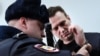 A Russian policeman removes handcuffs from Kremlin critic Aleksei Navalny, who was arrested during a March 26 anticorruption rally, during an appeal hearing at a court in Moscow on March 30.