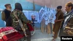 Taliban militants gather next to a picture of their leader, Mullah Haibatullah Akhundzada, in Kabul on August 25.