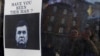 People look at a "Wanted" notice for fugitive President Victor Yanukovych, which was plastered on the window of a car used as barricade, near Kyiv's Independence Square on February 24