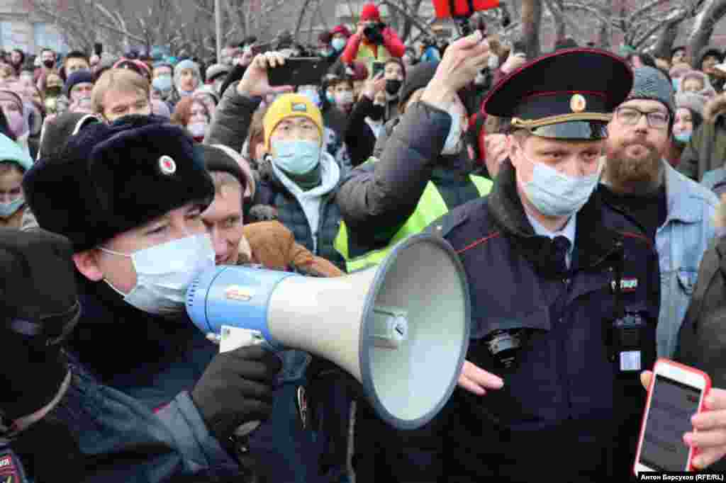 Police with megaphones speak to protesters during a rally in support of Navalny in the Siberian city of Novosibirsk.