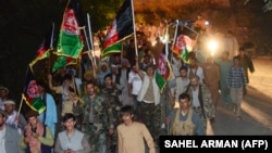 People wave the Afghan flag and chant slogans in support of the Afghan security forces fighting against the Taliban in Panjshir Province.