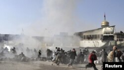 People react seconds after a suicide blast targeting a Shi'ite Muslim gathering in Kabul on December 6. Fifty-five people were killed and over 160 injured.