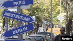 A pedestrian walks past symbolic road signs showing European cities in the Albanian capital of Tirana on November 7.