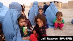 People who were displaced by fighting wait for government assistance at a temporary shelter in Herat Province on July 8.