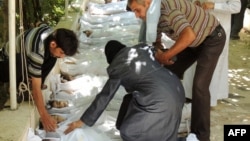 A woman mourns over one of the shrouded bodies of children and other victims that Syrian rebels claim were killed in a toxic gas attack by pro-government forces in eastern Ghouta on August 21.