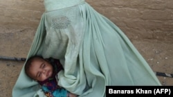 An Afghan refugee woman holds her baby at a United Nations repatriation center on the outskirts of Quetta, Pakistan.