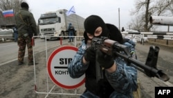 One of the armed masked men who call themselves members of Ukraine's disbanded elite Berkut riot-police force aims his rifle at a checkpoint on a highway that connects Crimea to mainland Ukraine near the city of Armyansk on February 28