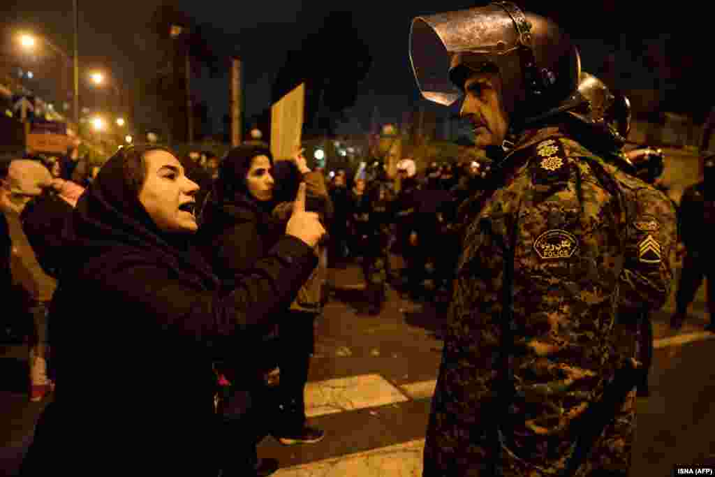 A woman attending a candlelight vigil for the victims of the Ukrainian airliner crash talks to a policeman on January 11 at Tehran&#39;s Amir Kabir University.