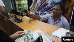 A woman counts U.S. dollars at a currency-exchange shop in a Tehran shopping center on October 3.