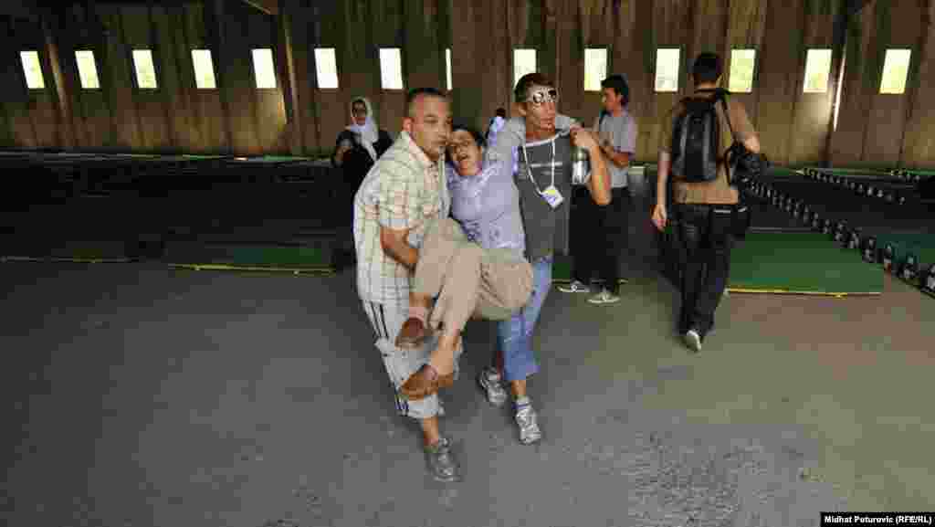 A woman is helped away from the area where the caskets are being stored after being overcome with emotion at the Potocari cemetery on July 10.