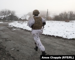 A Ukrainian soldier running while in view of nearby Russia-backed separatist positions in the Luhansk region on December 7.