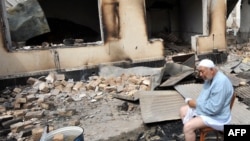 An elderly ethnic Uzbek man sits in front of his burned-out house in Osh.