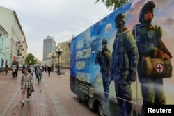 Pedestrians walk past a mobile recruitment point promoting service in the Russian Army and inviting volunteers to sign a contract, in Moscow on May 3.