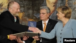 Danish cartoonist Kurt Westergaard (left) is congratulated on his prize by German Chancellor Angela Merkel (right) at the M100 Media Prize ceremony in Potsdam on September 8