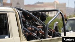 Huthi police ride on the back of a pick-up truck during the funeral of Huthi fighters killed in U.S.-led strikes in Sanaa on February 10.