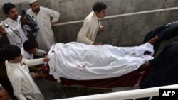 Pakistani paramedics move the body of a female polio-vaccination worker to a hospital following a deadly attack by gunmen in Peshawar on May 28. 