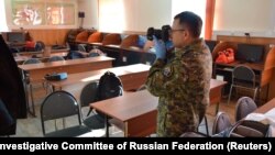 An investigator take pictures in a college classroom after a student shot and killed a fellow student and wounded three others before committing suicide in Blagoveshchensk on November 14.