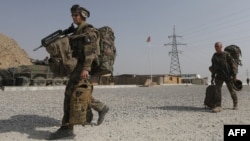 French soldiers from the 92nd Infantry Battalion leave with their backpacks as the Afghan national flag flies after an official handover ceremony of the Forward Operating Base Tora Surobi on July 31.