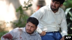 An injured United Nations employee rests outside his agency's office after a suicide blast in Islamabad.