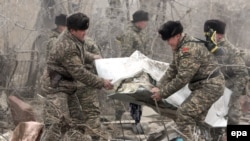 Kyrgyz servicemen carry a body bag with a victim at the crash site of a Turkish cargo plane in the village of Dacha-Suu outside Bishkek, which killed 28 people earlier this week. 